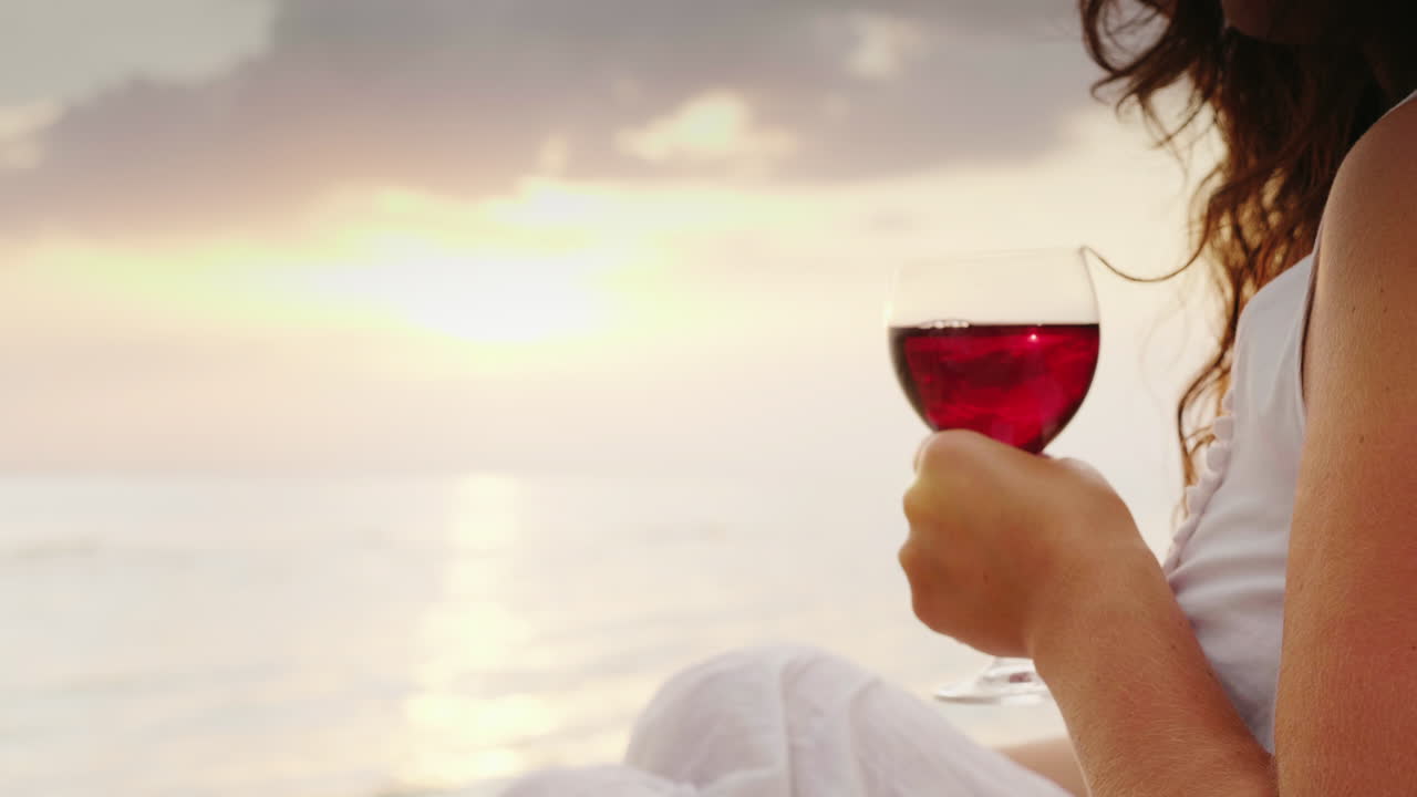 The Hands Of Men And Women Hold Glasses With Wine They Cling To Them Against The Background Of The S