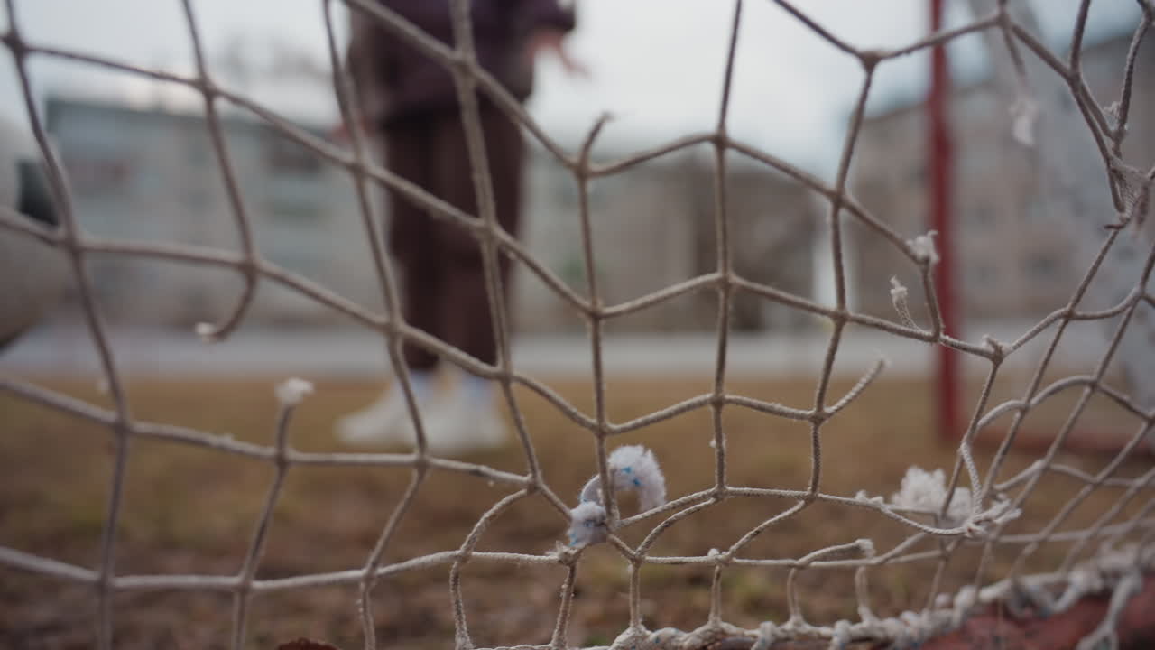 ball contacts net, scene capturing ball striking net close up, action shot of ball hitting net with grass background, dynamic moment showing ball making contact with net during game on urban field