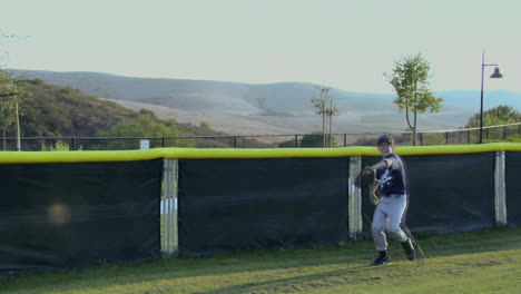 Ein-Junger-Baseballspieler-Fängt-Einen-Ball,-Als-Er-Fast-über-Den-Hinteren-Zaun-Fliegt