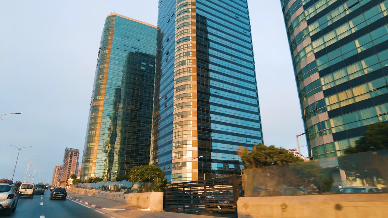 fotografía de los edificios de la ciudad de orán con palmeras al costado de la carretera al atardecer.