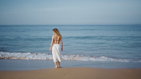 woman relaxing ocean shore walking on foamy waves alone. relaxed model strolling