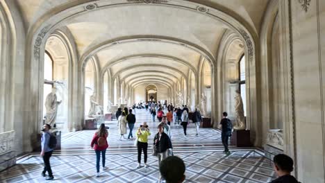 people walking through louvre museum's grand hallway