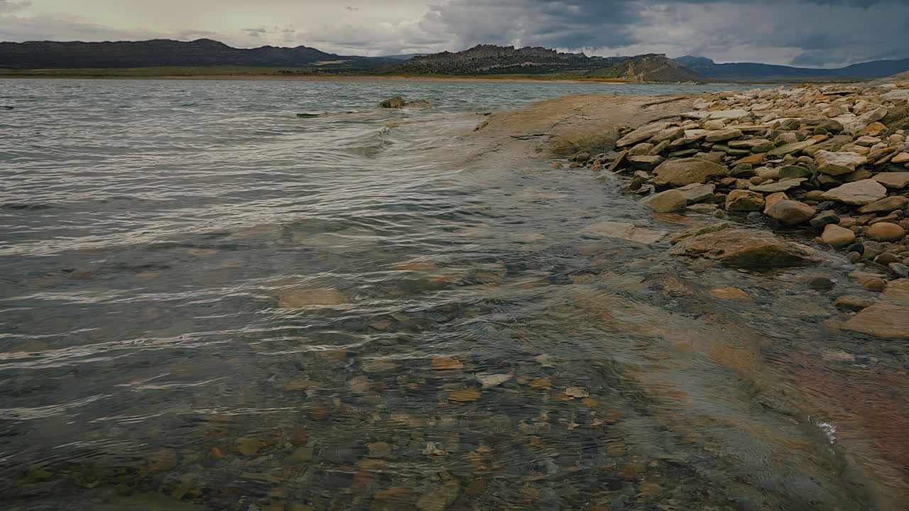 바위 와 바위 가 있는 호수 에 있는 바람 으로 움직이는 파도