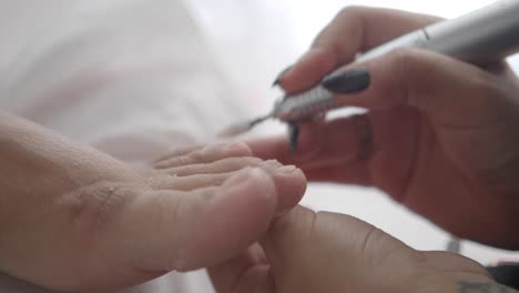 close-up of a professional performing a pedicure with an electric nail file