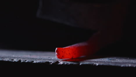 closeup slomo, red hot iron on anvil being hit with hammer as scale fly off