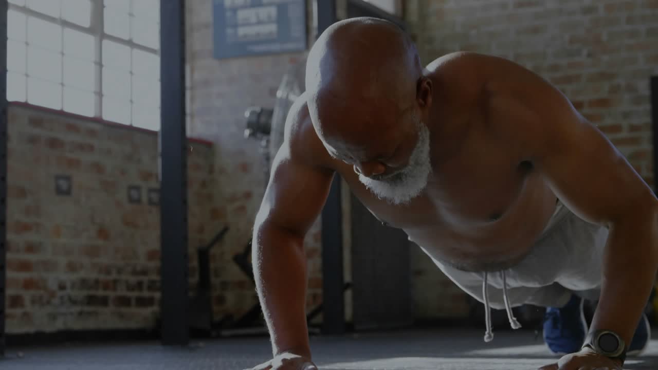 Uomo maturo che inizia facendo plank alto e piegamenti in una palestra tipo loft, HUD che mostra parametri che guidano l'esercizio con un braccio solo