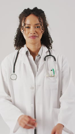 video vertical de una mujer médica biracial feliz mirando a la cámara