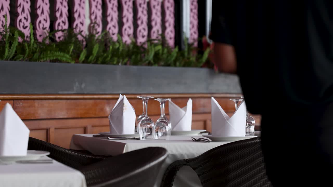 푸켓의 한 식당에서 웨이터가 테이블을 정리하며, 우아한 테이블 설정과 부드러운 조명으로 조용한 분위기를 보여줍니다.