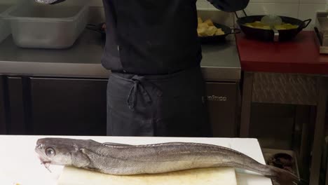 el chef presenta una merluza grande lista para cortar y limpiar.
