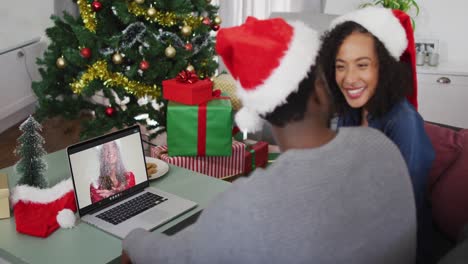 Glückliches-Afroamerikanisches-Paar-Bei-Einem-Videoanruf-Auf-Dem-Laptop-Mit-Einer-Freundin-Zur-Weihnachtszeit