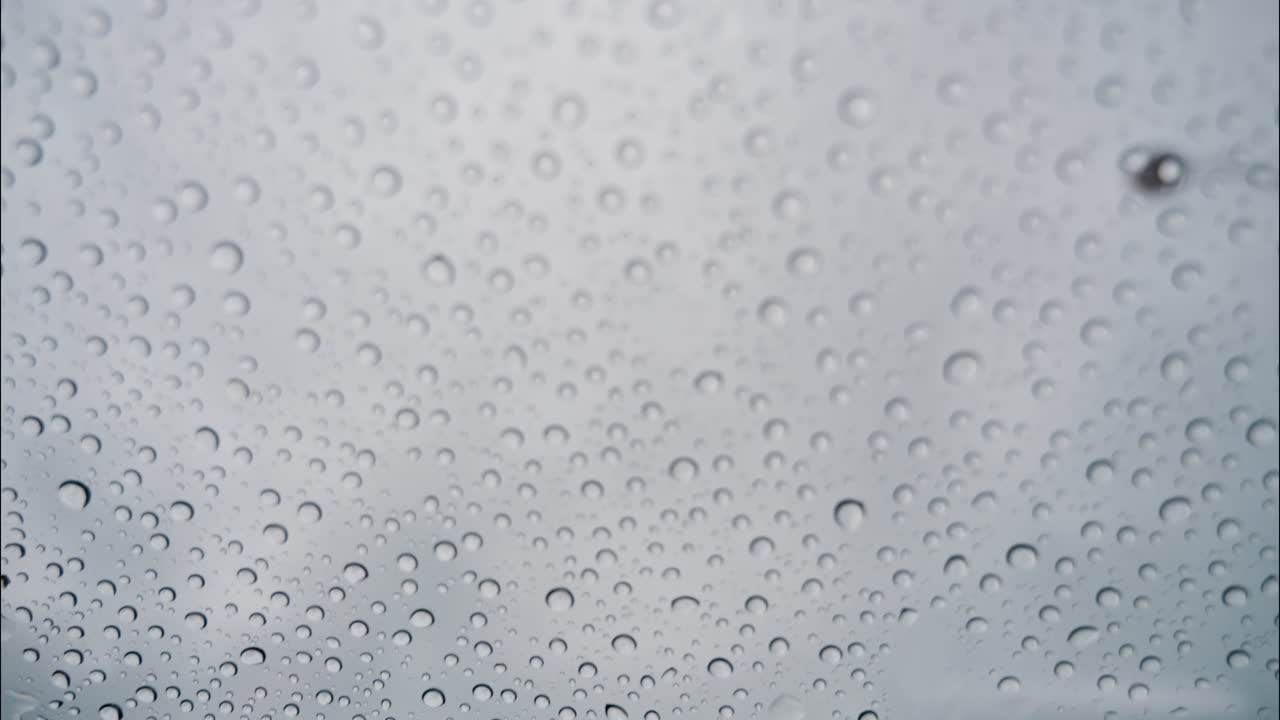 Close up of rain drops on a window with a view of a cloudy sky