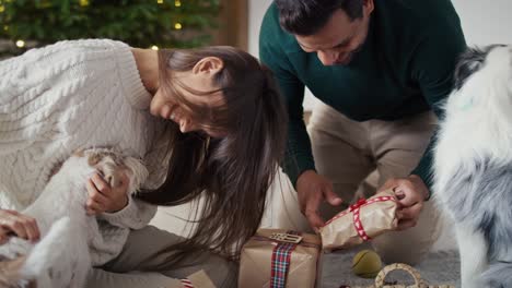 Glückliches-Paar-Aus-Mehreren-Ethnien,-Das-Geschenke-Packt-Und-Zu-Hause-Spaß-Mit-Dem-Hund-Hat.