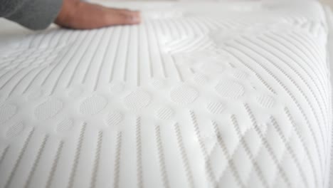 close up of a white mattress being touched by a hand