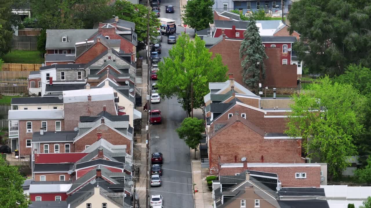 Row of houses Long street in American town at summer day. Aerial tilt up zoom shot. Lancaster city neighborhood at daytime. Cars parking along road. Pa, USA.
