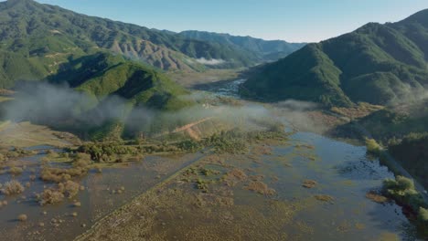 Aerial-drone-view-of-Te-Paranui-flooded-wetland-ecosystem-in-rolling,-rugged-mountainous-landscape-in-South-Island-of-New-Zealand-Aotearoa