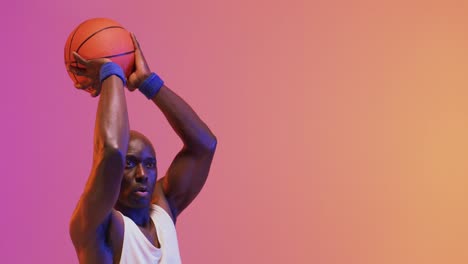 video de un jugador de baloncesto afroamericano lanzando una pelota sobre un fondo de color rosa a naranja