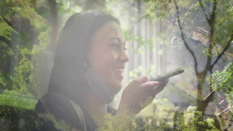 animation of happy biracial woman using smartphone over landscape