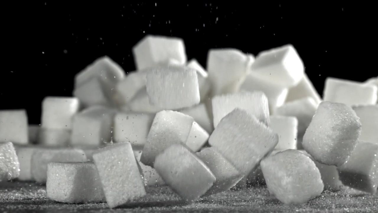 Terrones de azúcar cayendo en cámara lenta sobre fondo negro
