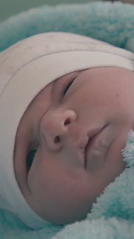 adorable little baby in warm fluffy blue suit and hat lies on changing table in light room extreme close view