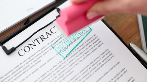 a hand stamping a contract document with "recommended"