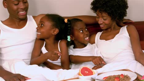 Familia-Sonriente-Desayunando-En-La-Cama