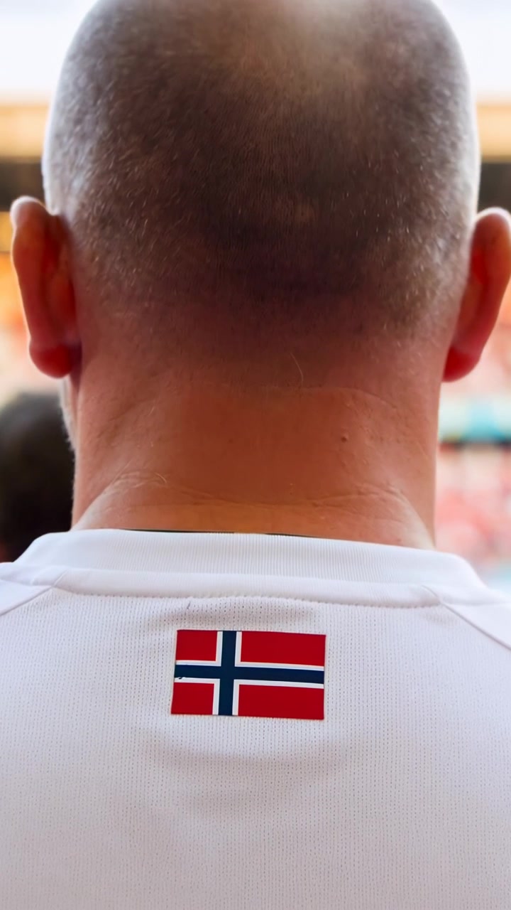 Vertical video: Zooming camera capturing man in white jersey at stadium highlighting Norwegian flag