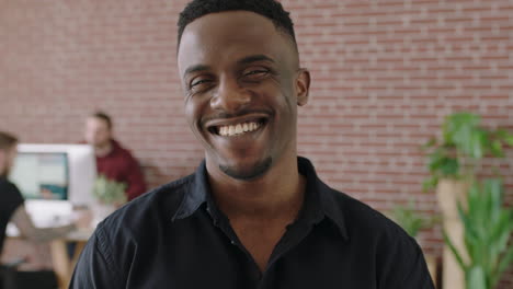 retrato de un atractivo joven afroamericano sonriendo feliz disfrutando de un exitoso negocio de inicio hombre negro en el espacio de trabajo de la oficina contemporánea