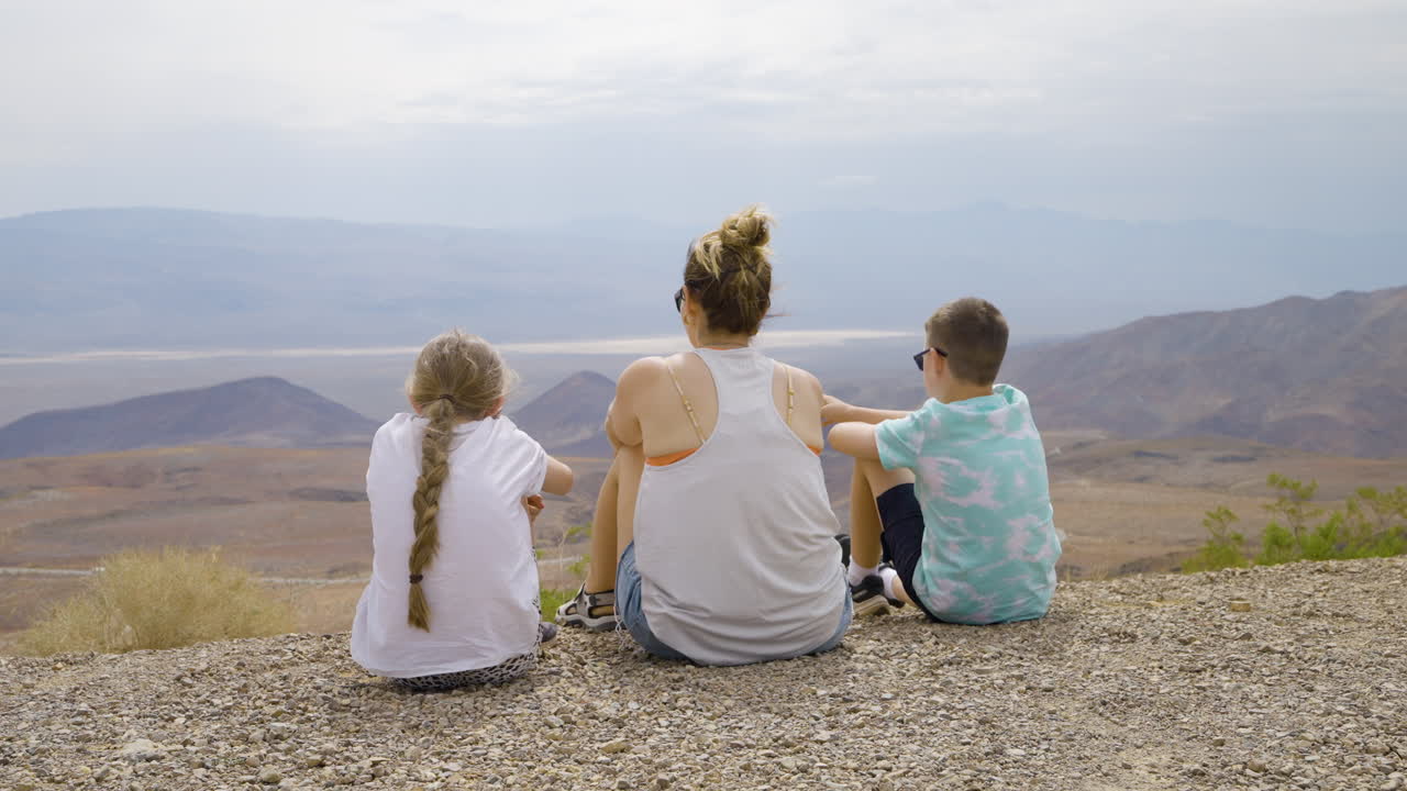 Family sitting on a hilltop enjoying the panoramic desert and mountain view