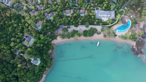 blue turquoise bay along a white sand beach coastline with luxury resort on jungle island, aerial