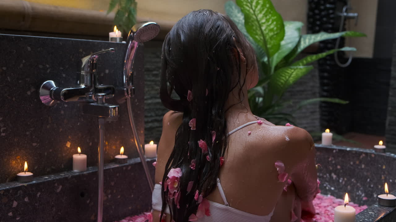 mujer disfrutando de un relajante baño de pétalos de rosa