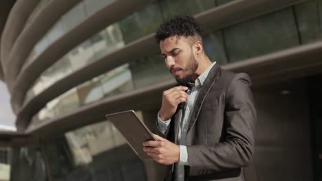 hombre serio y seguro de sí mismo con ropa formal sosteniendo una tableta