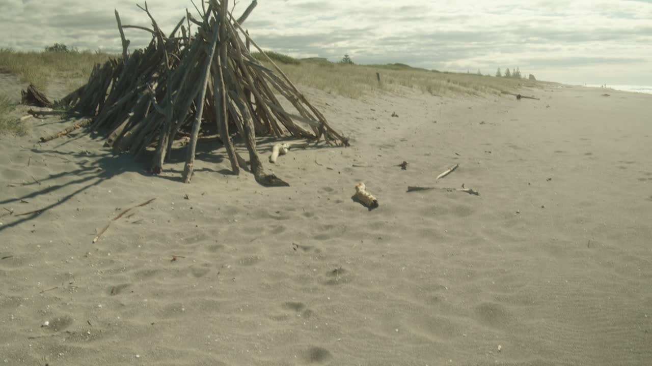 Tilt-up reveal shot of a bonfire on a sandy beach of New Zealand