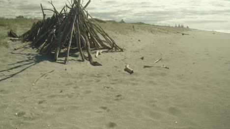 tilt-up reveal shot of a bonfire on a sandy beach of new zealand