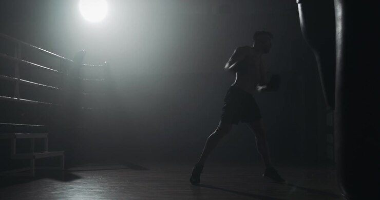 Silhouette al rallentatore di un pugile che si allena con un sacco da boxe