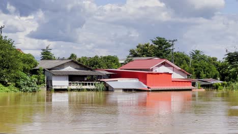 riverside houses inundated in overflowing river due to flash floods in northern thailand