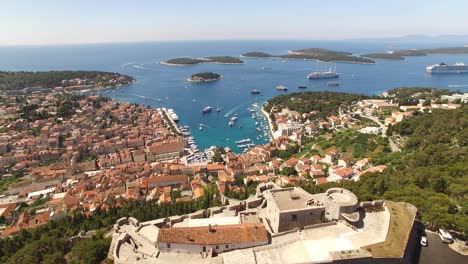 Eine-Luftaufnahme-Von-Hvar-Kroatien-Hebt-Die-Tvrdava-Fortica-Und-Die-Boote-Hervor,-Die-In-Den-Hafen-Einlaufen