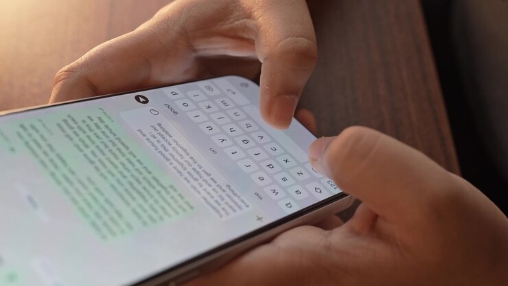 Woman's hand chatting and typing on a smartphone, macro closeup. Unrecognisable human typing a text message, tapping the touchscreen keyboard using the WhatsApp application, a social media.