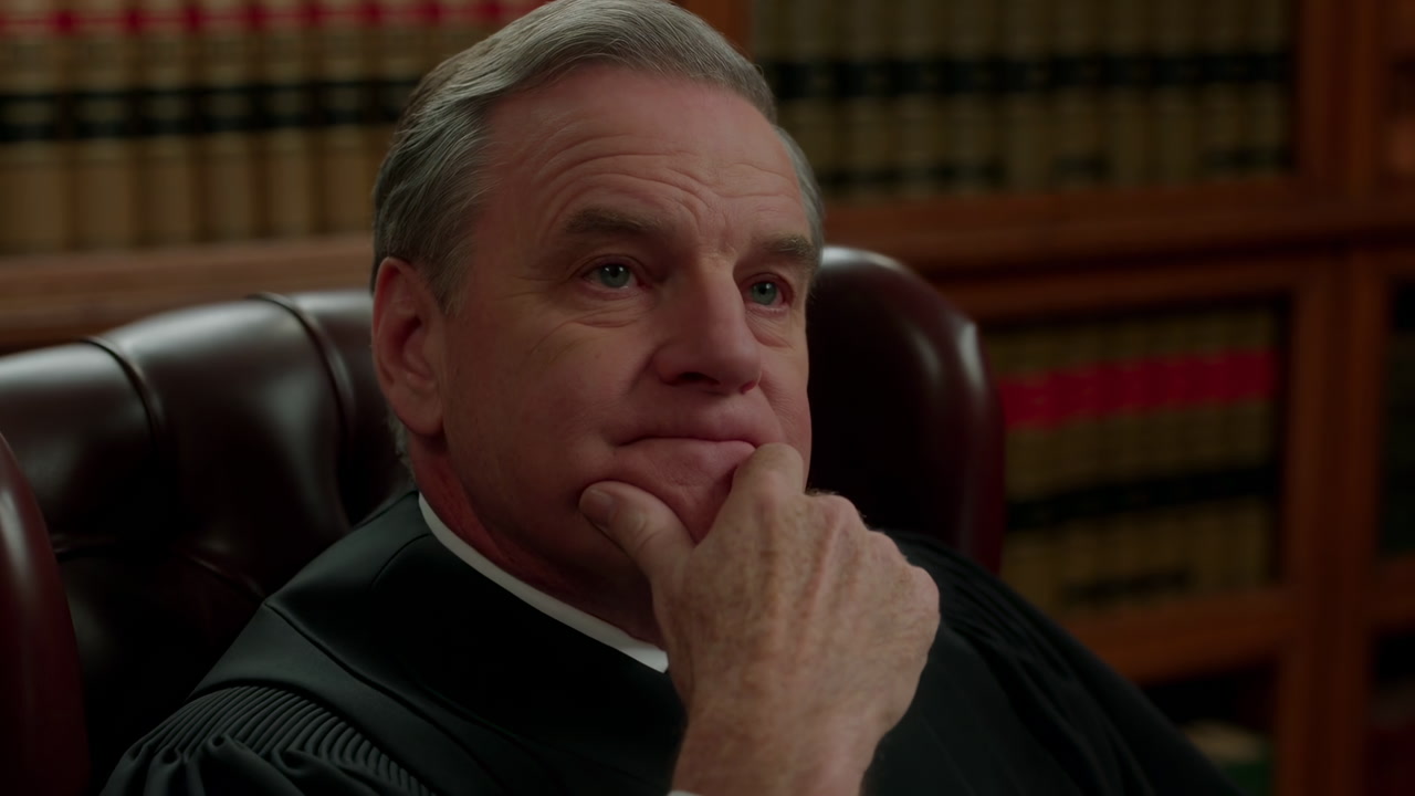 White Judge Reviewing Casebook In Chambers, Seasoned Jurist In Robe Leans In Leather Chair Among Rows Of Law