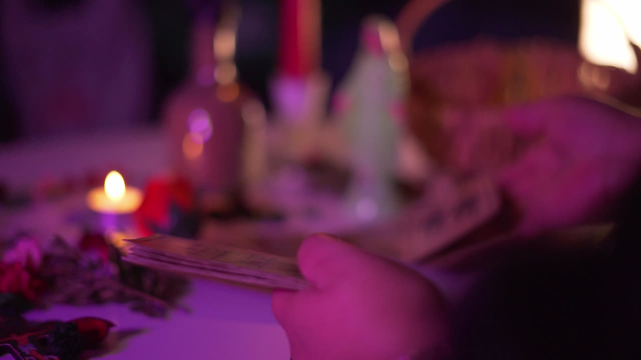Tarot card reading session with hands revealing mystical cards under moody purple light, shuffling to prepare