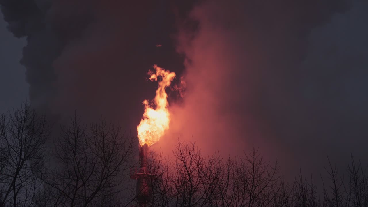 quema de gases peligrosos en la pila de bengalas de una refinería de petróleo durante la noche