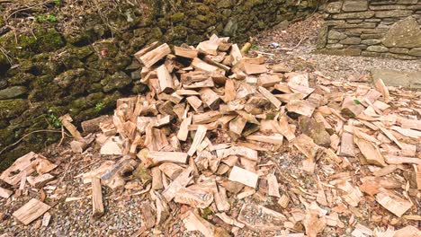 firewood pile grows against stone wall