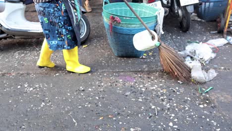 person sweeping litter into a blue basket