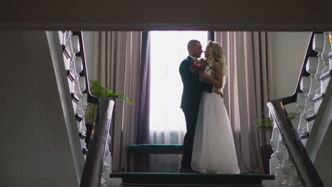 pretty bride and happy groom meet halfway on staircase