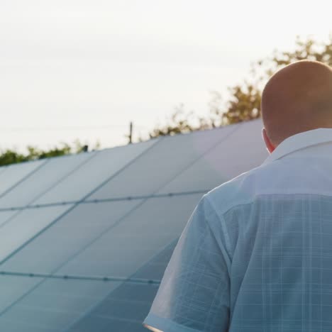 Vista-Posterior:-El-Propietario-De-La-Planta-De-Energía-Doméstica-Camina-A-Lo-Largo-De-La-Fila-De-Paneles-Solares