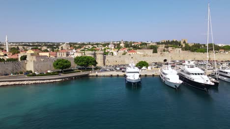 docked boats and yachts in kolona harbor and medieval city defense wall, aerial