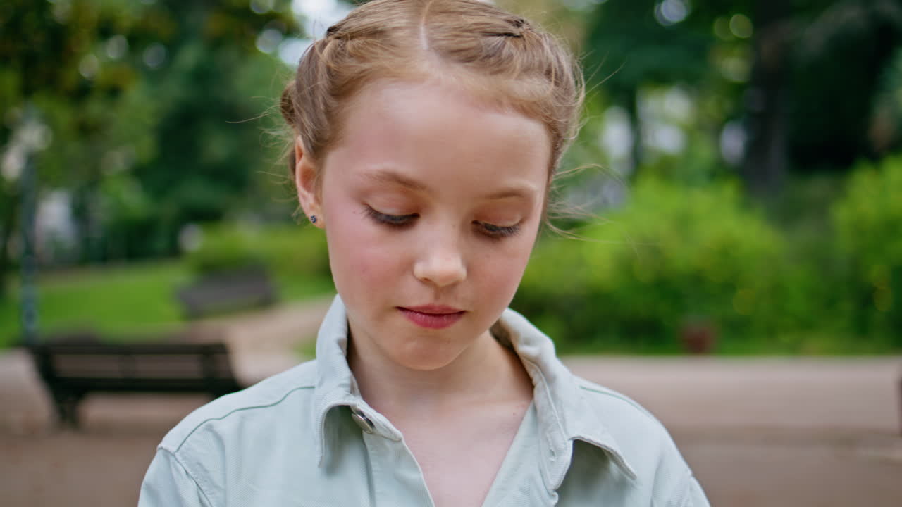 Girl blowing soap bubbles in green park portrait. Cute small kid playing closeup