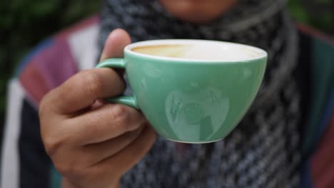 woman holding a green cup of coffee