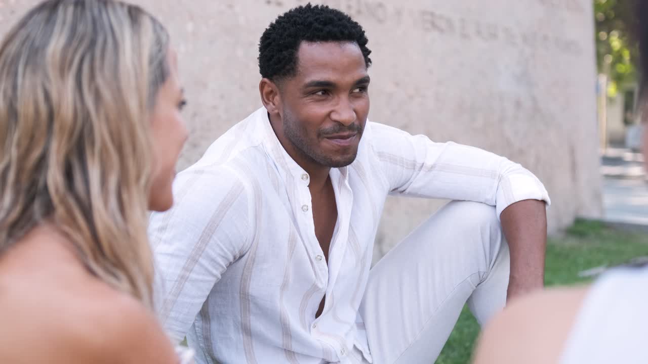 Diverse friends talking while sitting together at city park