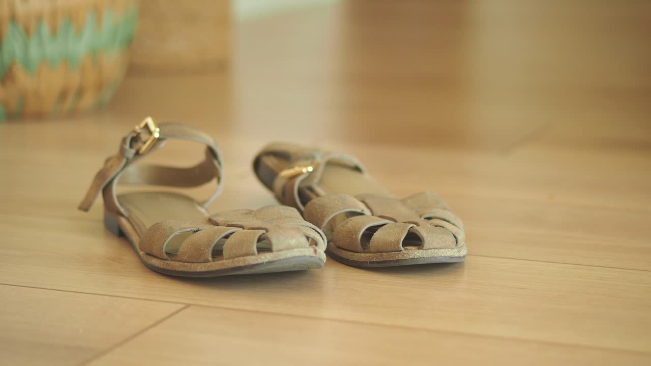 A pair of beige sandals on a wooden floor