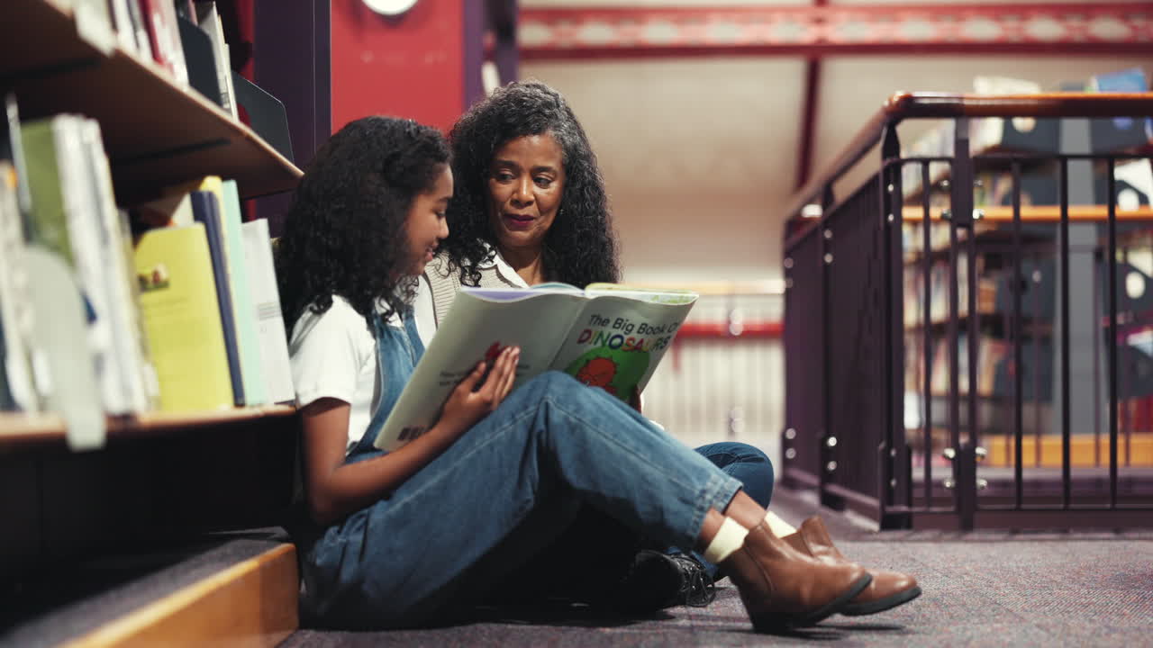 Frau und Mädchen lesen ein Buch in einer Bibliothek